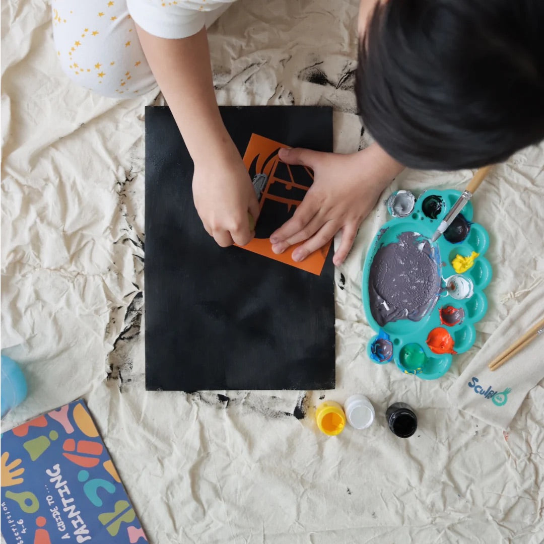 Child painting on a black canvas with Sculpd canvas painting kit
